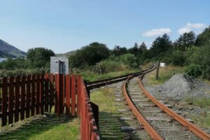 The image shows a set of rust - colored railway tracks curving through a lush, green landscape. Flanked by a red wooden fence on one side and surrounded by vegetation, the tracks lead the eye into the distance, where trees and a hint of a distant mountain can be seen. Just as these railway tracks serve as a pathway through the scenery, &ldquo;About BaoLiba – Connecting Irish Influencers & Brands to the World&rdquo; acts as a bridge. It paves the way for Irish influencers and brands to journey beyond their local boundaries, much like the tracks that extend into the expansive landscape, reaching a wider, global audience.